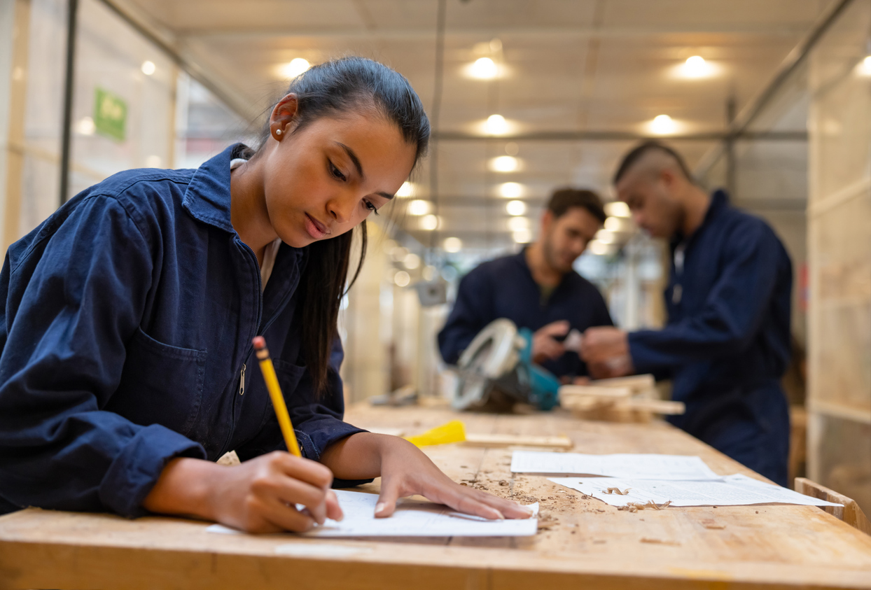 Young adult drafting plans in a skilled-trades workshop