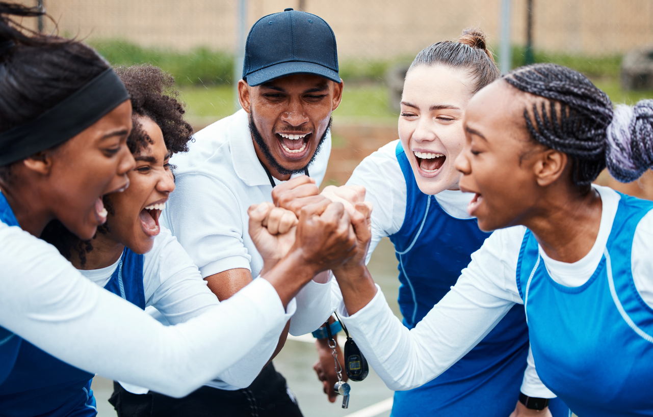 Coach and a youth team celebrating together in a huddle